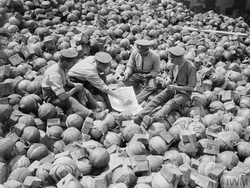 Soldiers playing cards on a pile of mortar ammunition